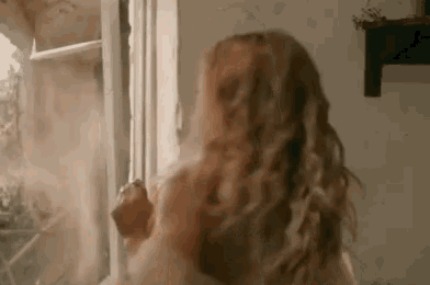 a woman is standing in front of a window with a smoke coming out of it .