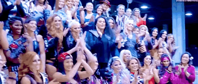 a large group of women are sitting in a stadium clapping .