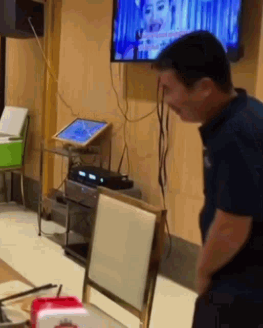 a man is standing in front of a television with a woman on the screen