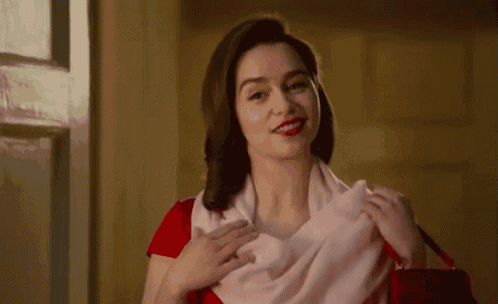 a woman wearing a red dress and a pink scarf is holding a red purse .