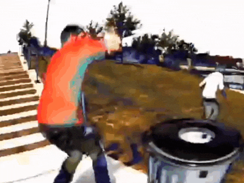 a man in a red vest stands next to a trash can