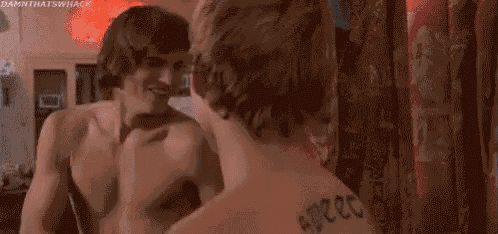 two shirtless men are standing next to each other in front of a store window .