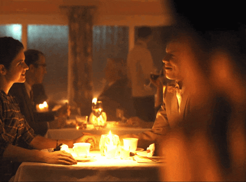 a group of people are sitting at a table with candles