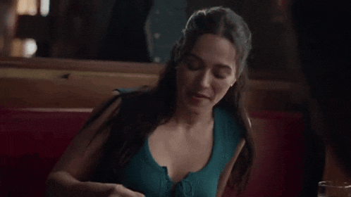 a woman is sitting at a table eating a sandwich .