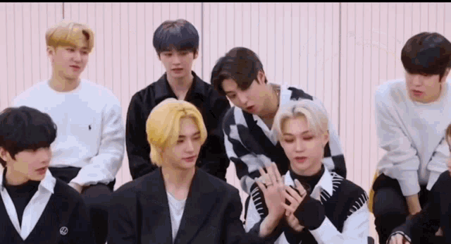 a group of young men are sitting next to each other in a room and holding hands .