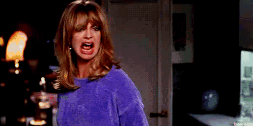 a woman in a purple sweater is screaming and making a funny face .