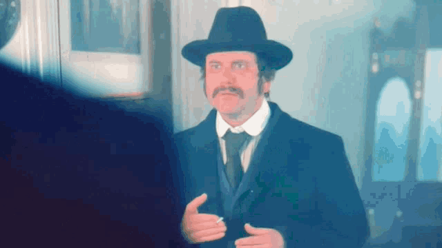 a man with a hat and a mustache is standing in a room