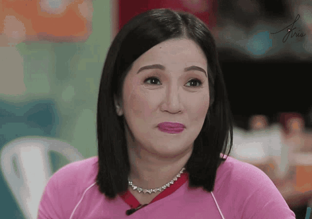 a woman wearing a pink shirt and a necklace