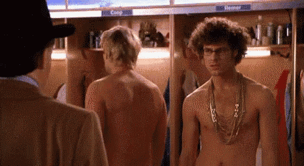 two shirtless men are standing in a locker room .