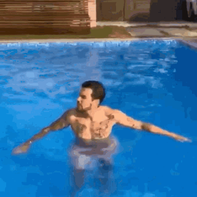 a shirtless man is floating in a swimming pool
