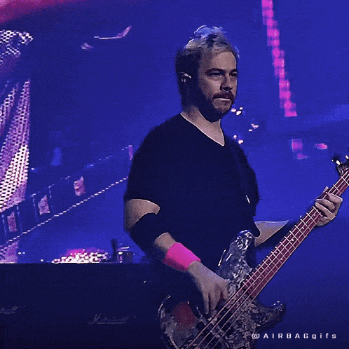 a man in a black shirt is playing a bass guitar