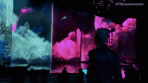 a man stands in front of a screen that says the game awards