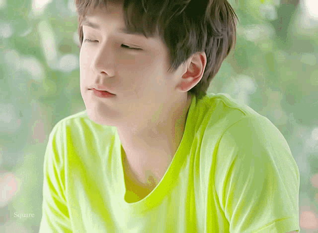 a close up of a person wearing a green shirt with the word square on the bottom