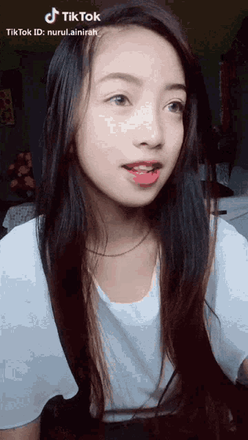 a girl with long hair and a white shirt has a tiktok id