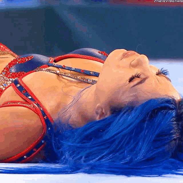 a woman with blue hair is laying on a blue surface