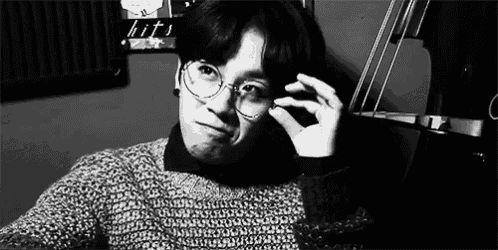 a young man wearing glasses and a sweater is taking a selfie .