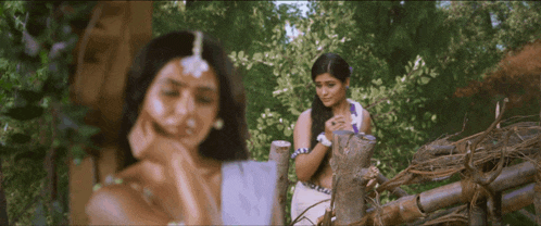a couple of women standing next to each other in a forest