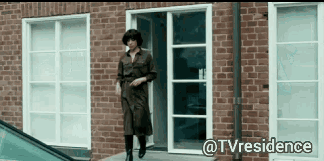 a woman is walking out of a brick building with the hashtag tvresidence
