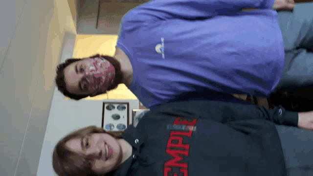 a man wearing a purple shirt is standing next to another man wearing a black hoodie with the word empire on it