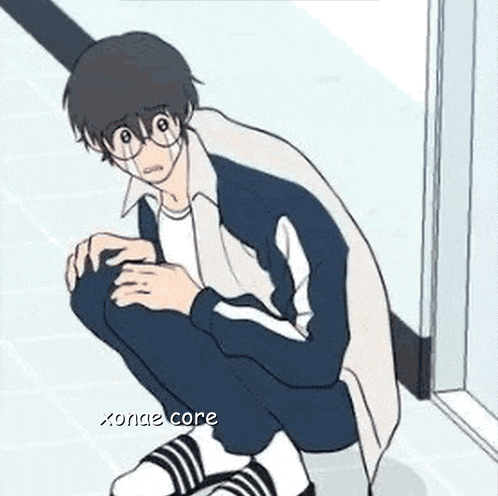 a boy with glasses is squatting on the floor .