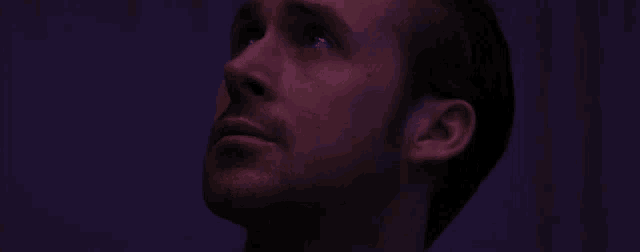 a man with a beard is looking up at the sky in a dark room