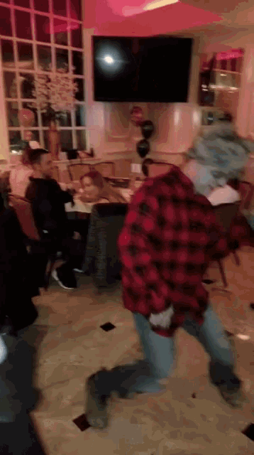 a man in a red plaid shirt is kneeling down in a room