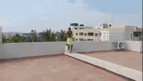 a man in yellow shorts is standing on a rooftop with an air conditioner