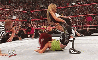 a wrestler is carrying another wrestler on her back in a wrestling ring .
