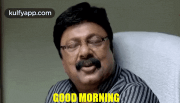 a man with glasses and a mustache is sitting in a chair and says good morning