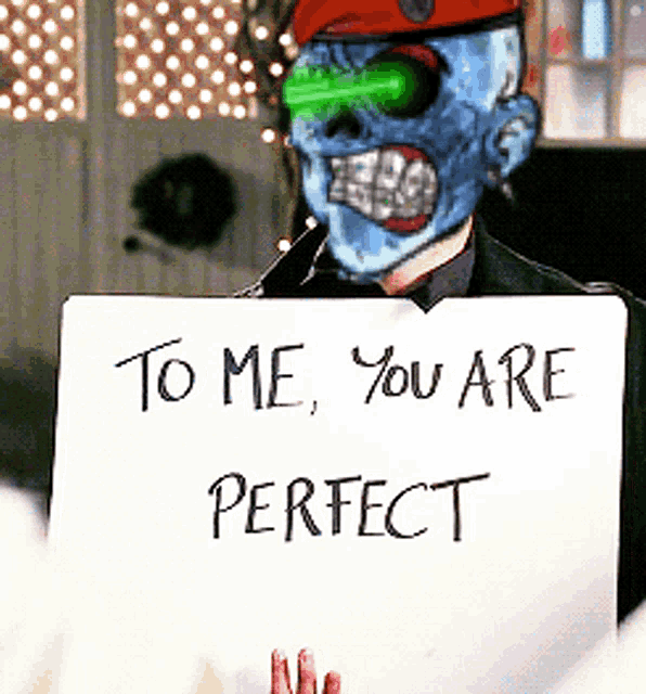 a man with a skull mask is holding a sign that says to me you are perfect