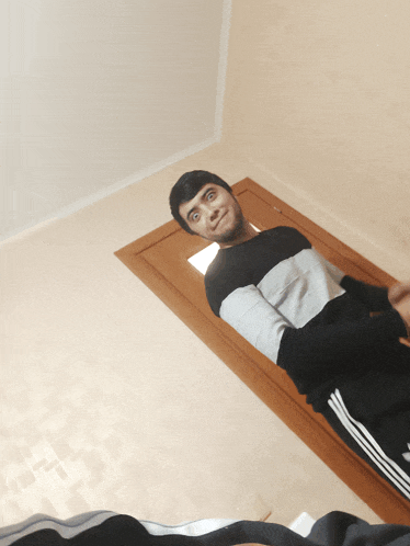 a man in a black and white sweater is laying on the floor in front of a door