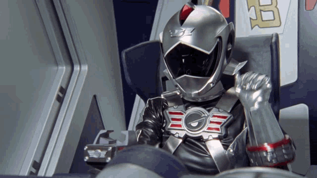a man in a helmet with the letter g on it sits in a chair