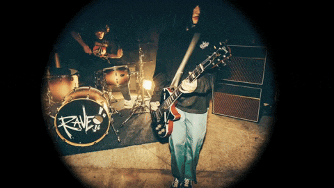 a man playing a guitar in front of a drum with the word raves on it