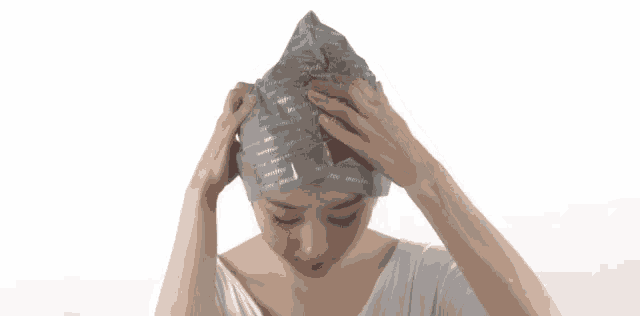 a woman is wearing a gray hat with a red ribbon around her head .