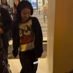 a woman wearing headphones and a mickey mouse sweater is walking in a room .