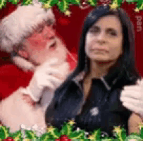 a woman is sitting next to a man in a santa suit .