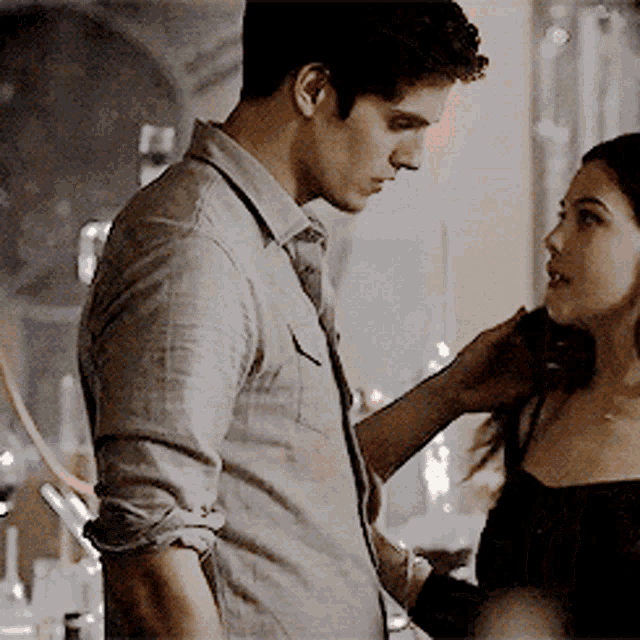 a man and a woman are standing next to each other and the woman is touching the man 's neck