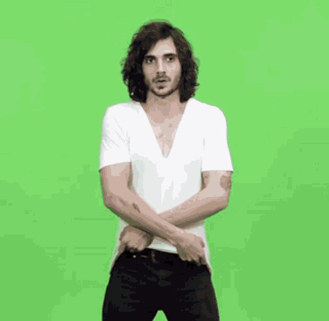 a man with long hair is wearing a white shirt and black pants