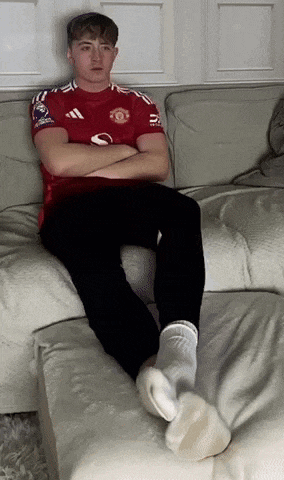 a man wearing a red adidas shirt is sitting on a couch