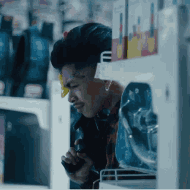 a man with a yellow sticker on his forehead is talking on a cell phone in a store