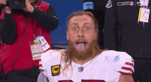 a man with a beard is sticking his tongue out while wearing a nfl jersey .