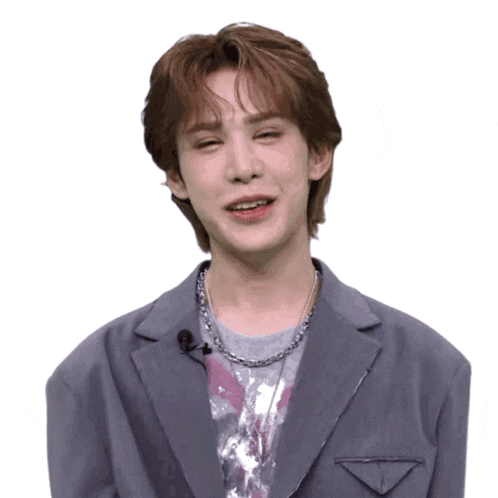 a young man wearing a gray jacket and a silver necklace makes a funny face