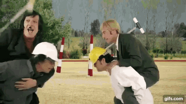 a group of men are standing in a field and one of them is carrying another man on his shoulders .