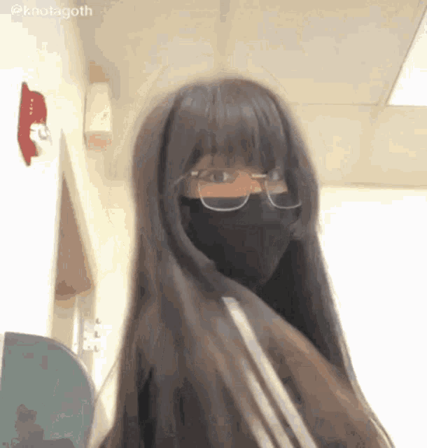 a girl with long hair and glasses is wearing a black mask .