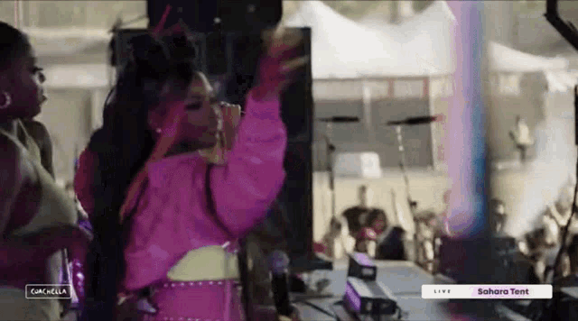 a woman in a pink sweater is dancing in front of a microphone at a concert .
