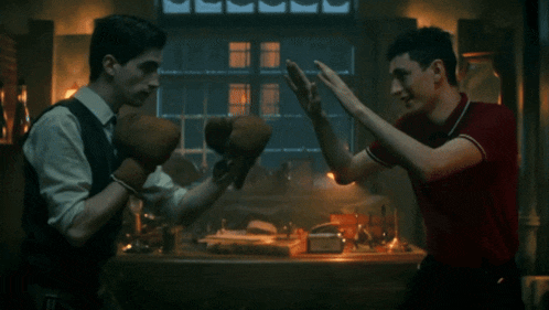 a man in a red shirt is giving another man a high five while wearing boxing gloves