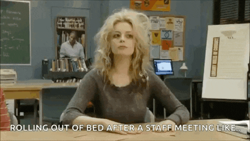 a woman is sitting at a desk in a classroom and rolling out of bed after a staff meeting like