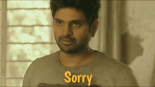 a man wearing a gray shirt that says sorry