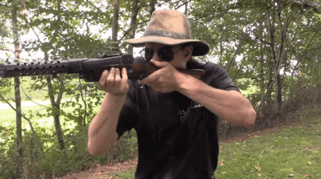 a man wearing a hat and sunglasses is pointing a gun