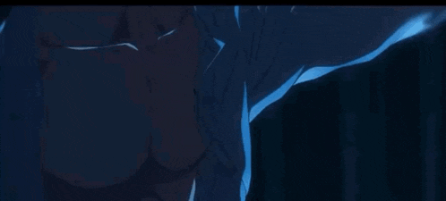 a man with a choker on his neck is looking at a cell phone in the dark .